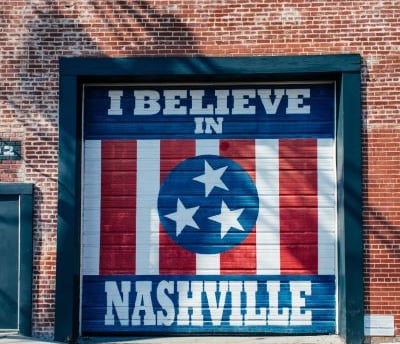 a garage door with a mural of a flag on it with the text “I Believe in Nashville”