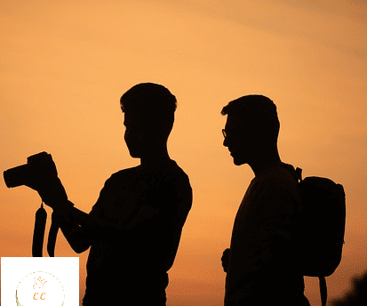 2 silhouettes d'amis, un homme tient un appareil photo
