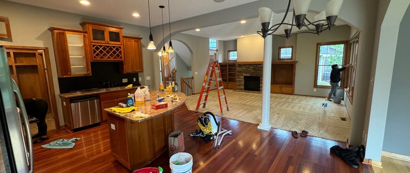 a kitchen with a wooden floor and a ladder with two cleaners