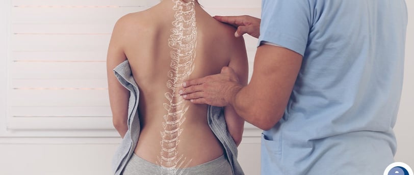 Um Fisioterapeuta examinando a região da coluna de uma mulher