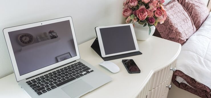 TechAid spec laptop computer sitting on a desk with a vase of flowers