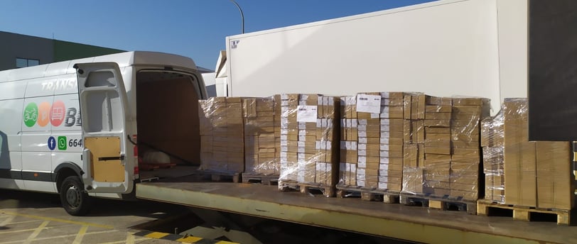 Furgoneta de Transportes Beal cargando pallets con mercancía en un muelle de carga.