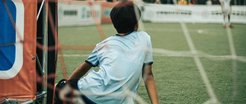 Kid sitting in front of a soccer goal