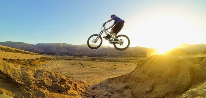Mountain biker hitting a canyon gap jump at sunrise, showcasing advanced freeride technique