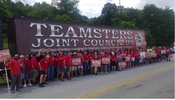 Large group in front of Teamsters truck with strike signs
