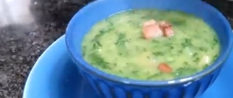 Mingau de couve com bacon, servido em uma tigela azul. O mingau tem uma textura cremosa e homogênea,