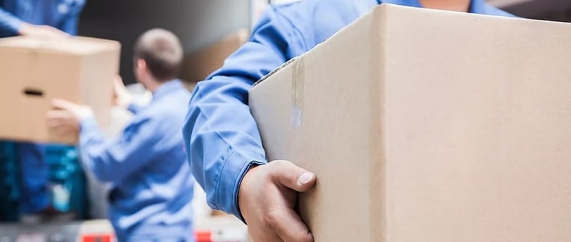 a man in a blue shirt is holding a box of boxes