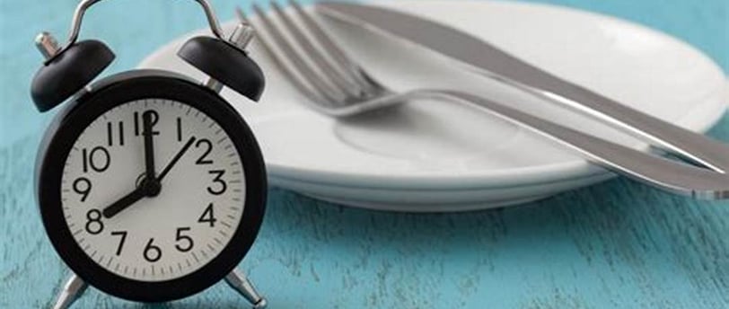 a clock on a plate with fork and fork