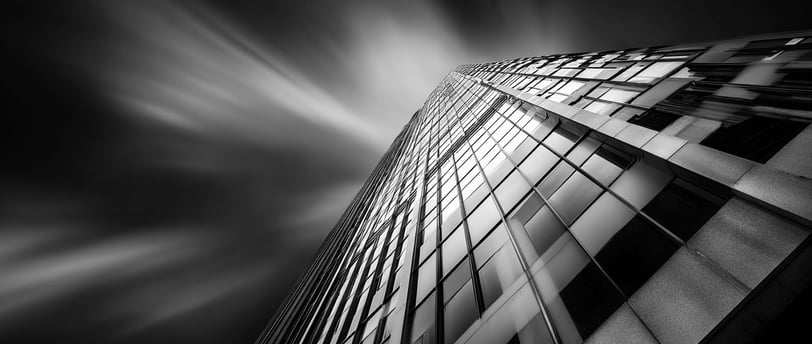 Abstract black and white photo of a glass skyscraper shot from a dramatic upward angle