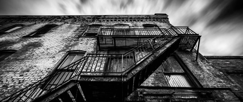 Old brick building with fire escape in motion sky.