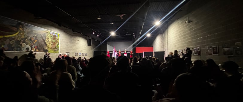 a crowd of people standing in a room with a stage