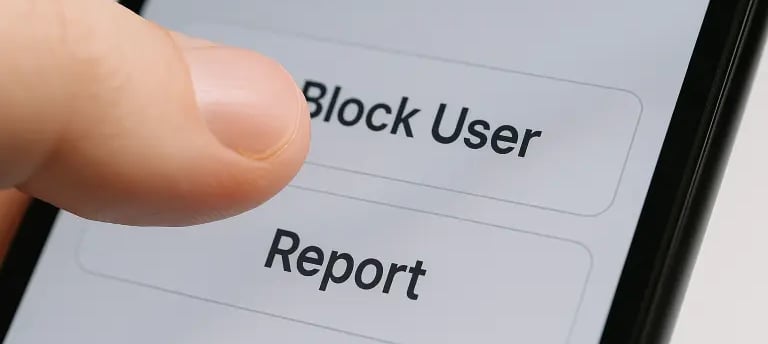 Dedo toca botão "Bloquear Usuário" em app, simbolizando proteção contra cyberbullying.