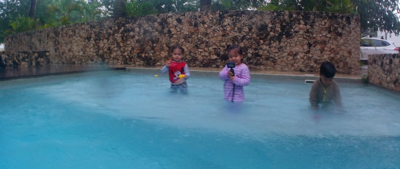 two children playing in a pool with a man and a woman
