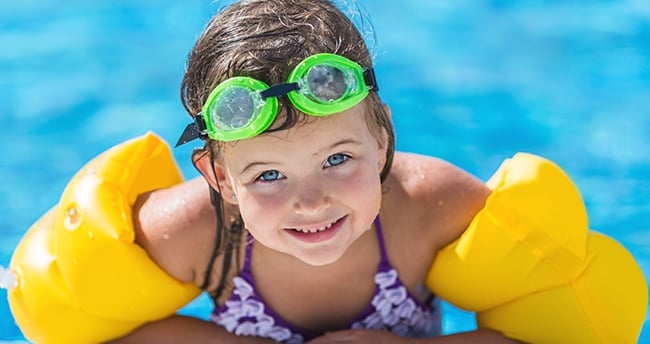 a young girl in a bikinisuit is laying on a swimming pool