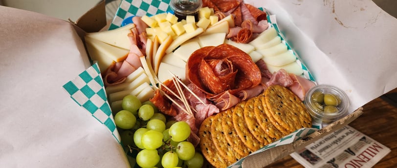 tabla de carnes frías y quesos de finca narvarte con uvas, galletas y aceitunas