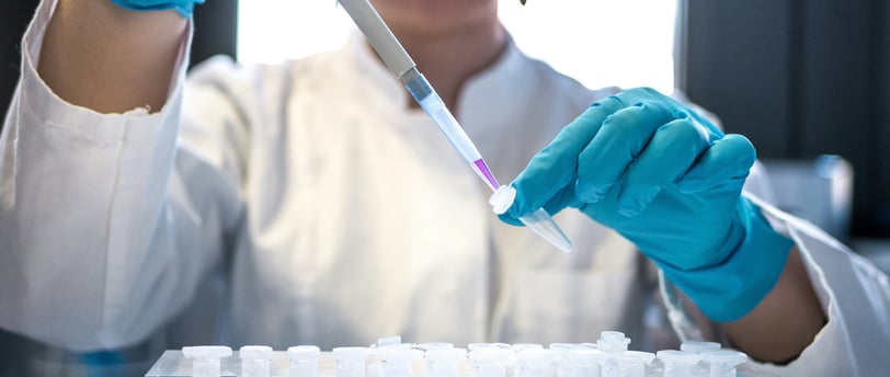 a woman in a lab coat and gloves holding a pipe of liquid