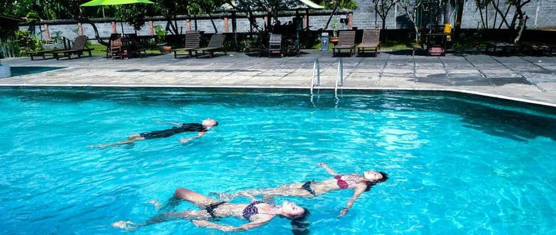 a woman swimming in a pool with two people for intro dive in bali