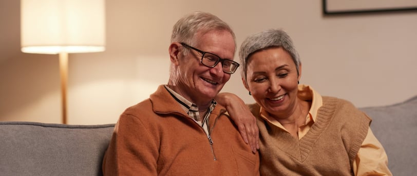 an older man and woman sitting on a couch