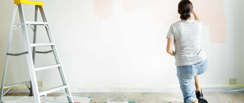 a woman is painting a wall with a ladder withe adom.ma