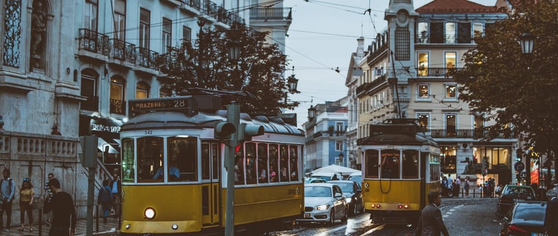 a yellow tram car is parked on the side of a street