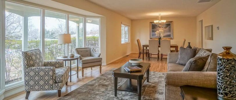 Living room with sofa, coffee table, and two chairs and dining room towards the back