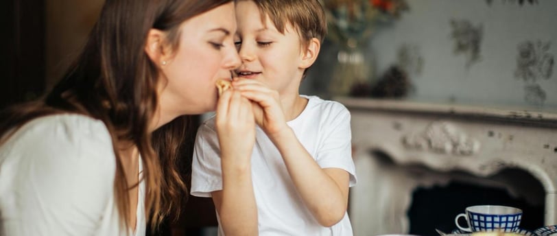 child feeding food to his mother