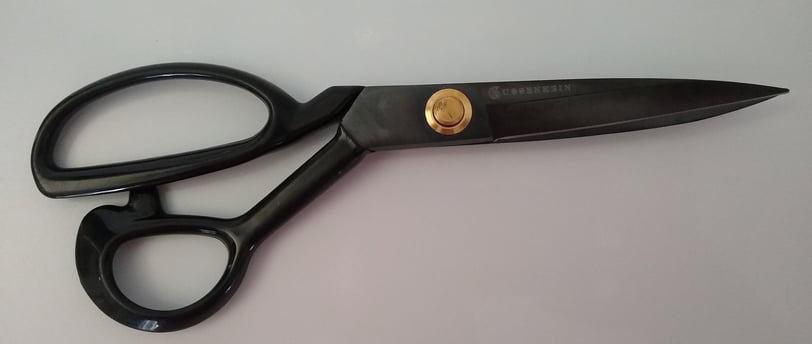 A pair of black Guggenhein sewing scissors with gold screw detail on a white background.