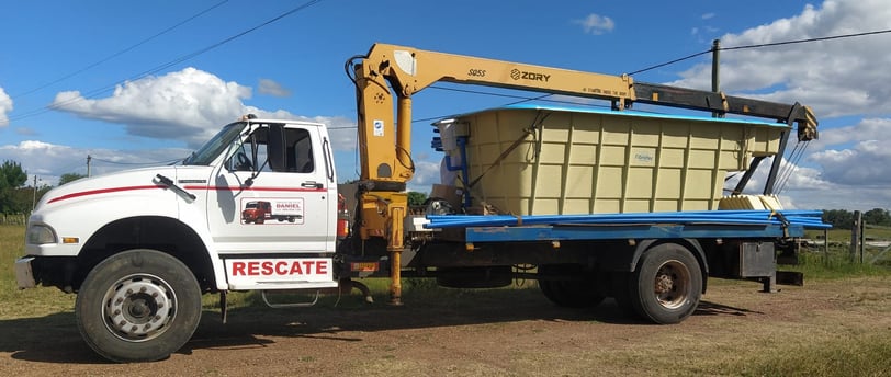 A truck with a large container on it, equipped with a telescopic boom truck mounted crane.