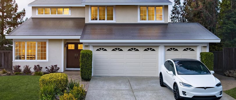 House with Tesla Solar Roof and White Tesla Electric Car parked in driveway