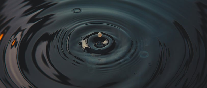 a droplet creating ripples in dark water