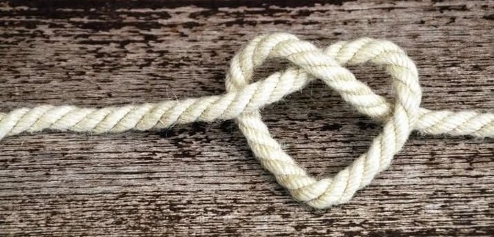 un cœur fait de corde posé sur une planche en bois   