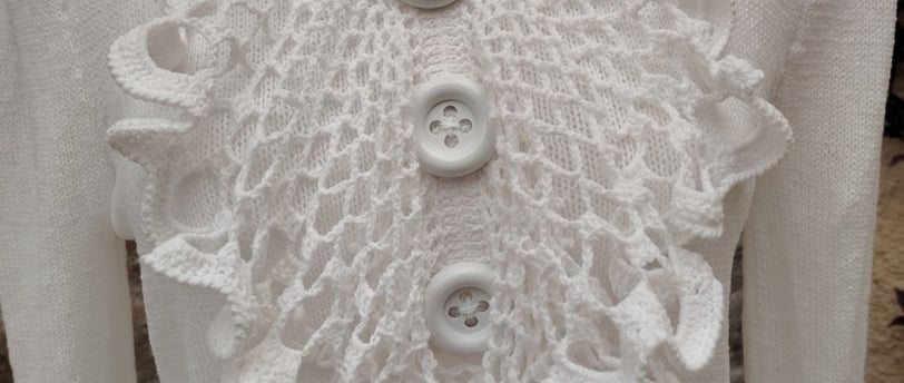 jabot sur un pull blanc deux gros boutons blanc son cousu dessus au milieu