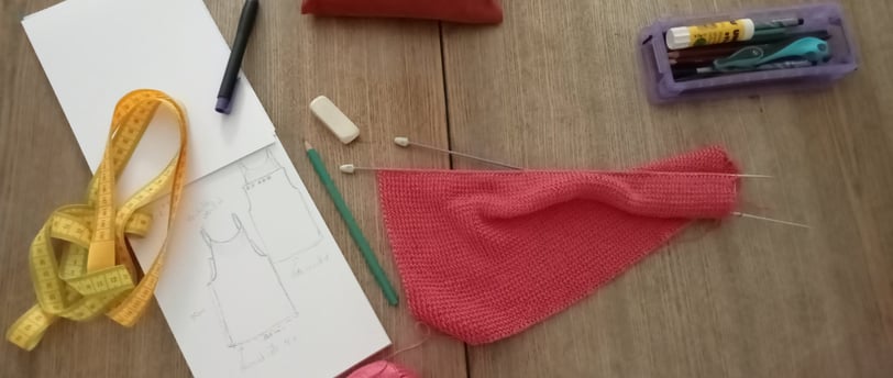 Posé sur une table un tricot et des aiguilles à tricoter un carnet à dessin des crayons une gomme