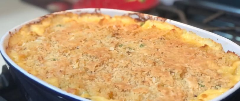 Cheesy classic tuna casserole baked in a dark blue ceramic casserole dish on top of a gas stove