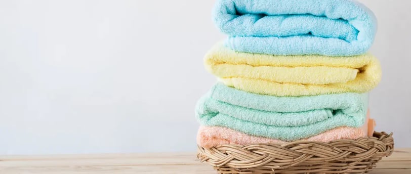 Stack of pastel-colored towels neatly arranged in a wicker basket.