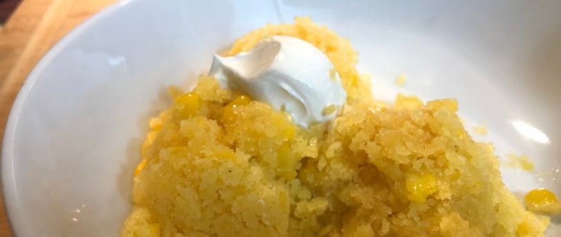 A bowl of moist Mexican corn cake topped with thick sour cream
