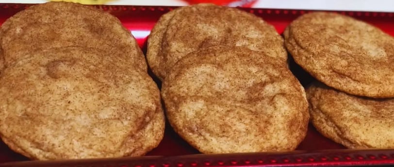 Tray of freshly baked snickerdoodle cookies arranged on a red baking tray.