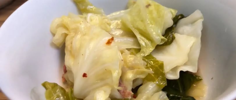 bowl of southern cabbage with smoked meat and red pepper flakes in broth