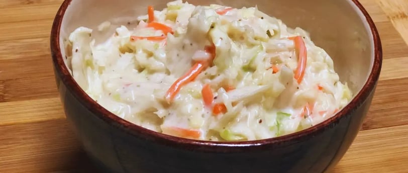 Sweet coleslaw in a blue bowl on a wooden table, creamy and ready to serve