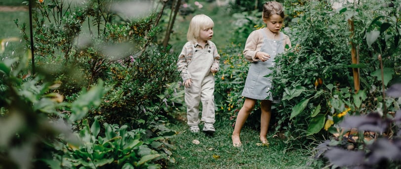 two children standing in a garden with flowers