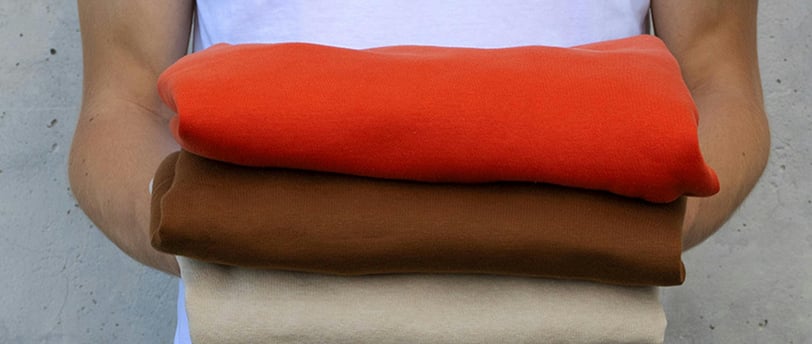 a man holding a stack of four different colored fabrics