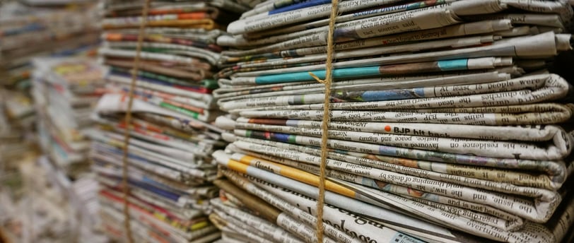 a bunch of newspapers and magazines stacked on top of each other