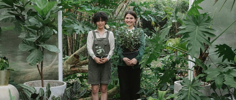 two women standing in a garden with plants