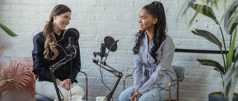 two women sitting in chairs with microphones