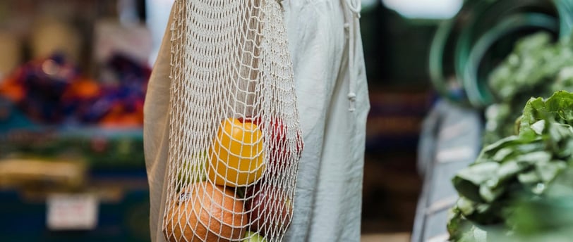 a woman in a white top and a bag of fruit and vegetables