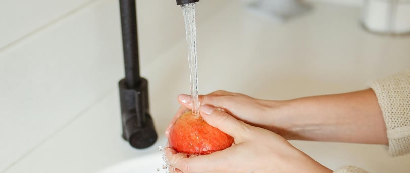 a person washing a red apple in their hand