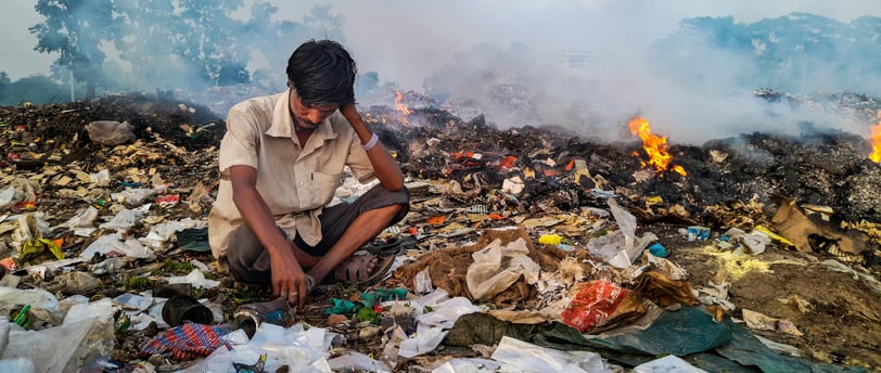 A person sitting on top of garbage while some of them are burning
