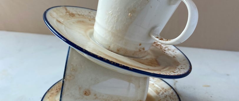 a stack of dishes with a cup of coffee and a mug