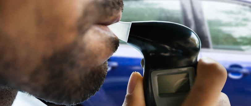 a man with a beard blowing into a breathalyzer