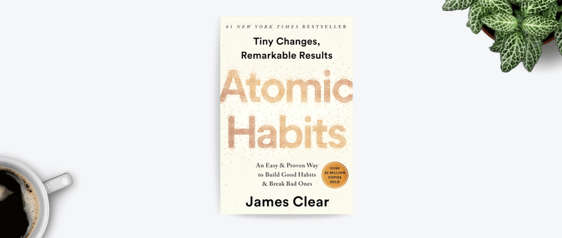 a cup of coffee and the book Atomic Habits on a table
